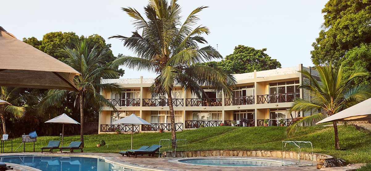 Coral Beach Resort's two-story guest wing and pool amid palm trees